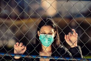Conceptual photo of captivity with young adult woman on it. Coronavirus concept. Girl wearing protective mask.-cm